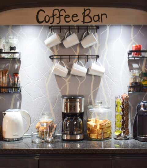 gallery illustrating coffee bar section of room with cups, coffee machine, rusks, kettle, coffee and sugar