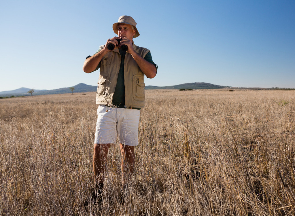 honoring dad with a safari experience with a man standing in a field holding binoculars